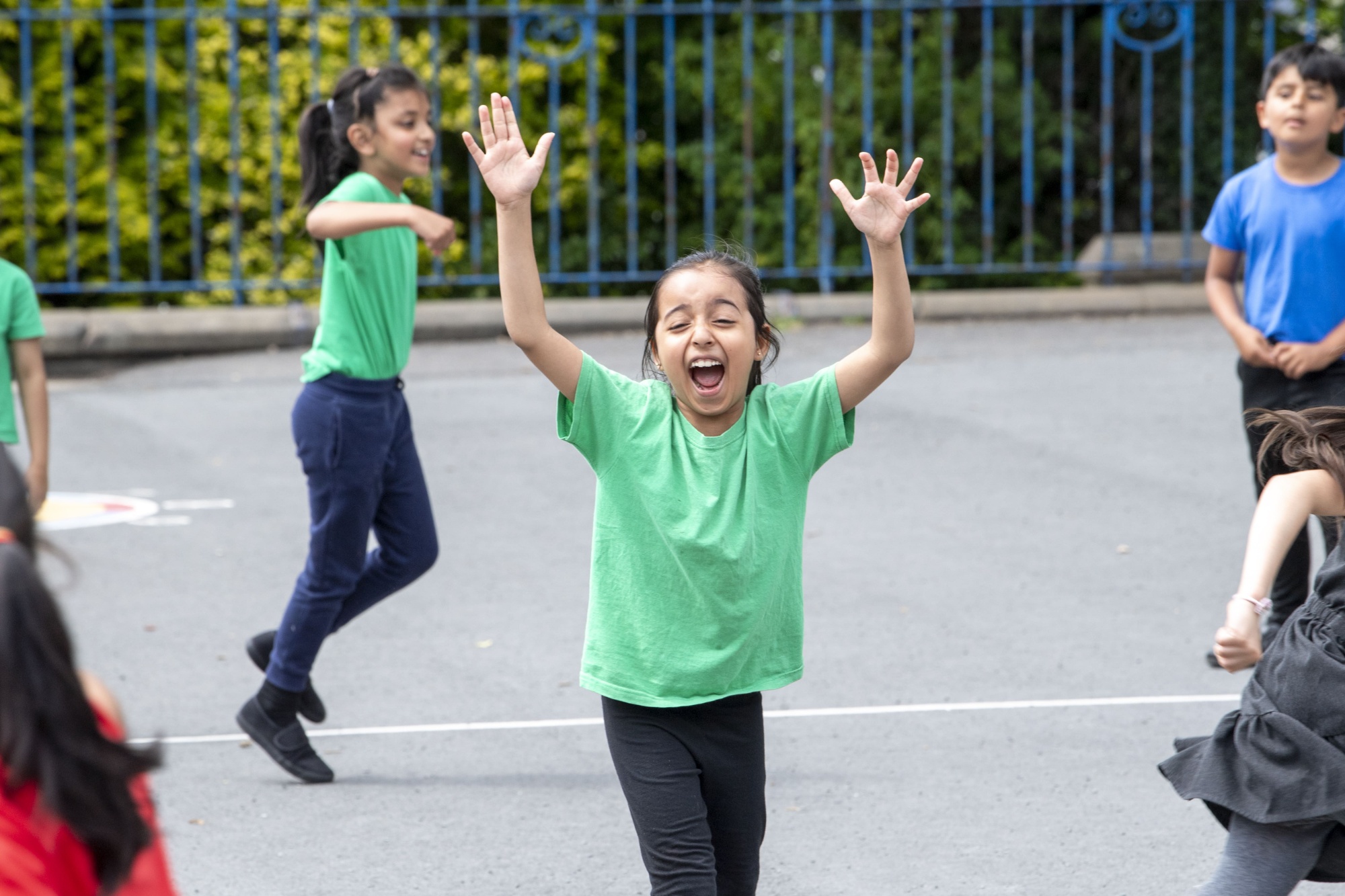 A girl with her hands in the air, cheering in a PE lesson