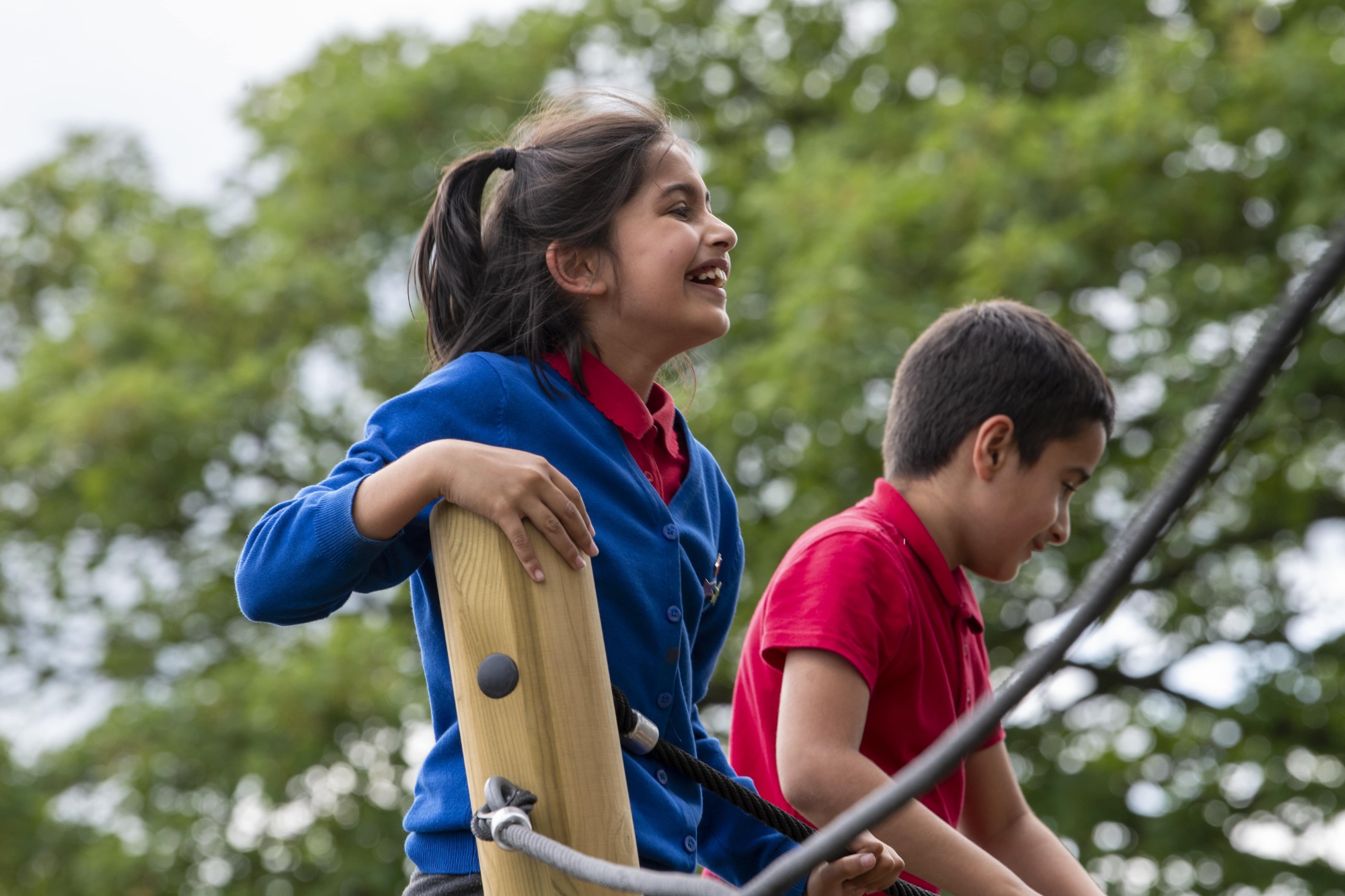 Two children smiling, playing on a climbing frame
