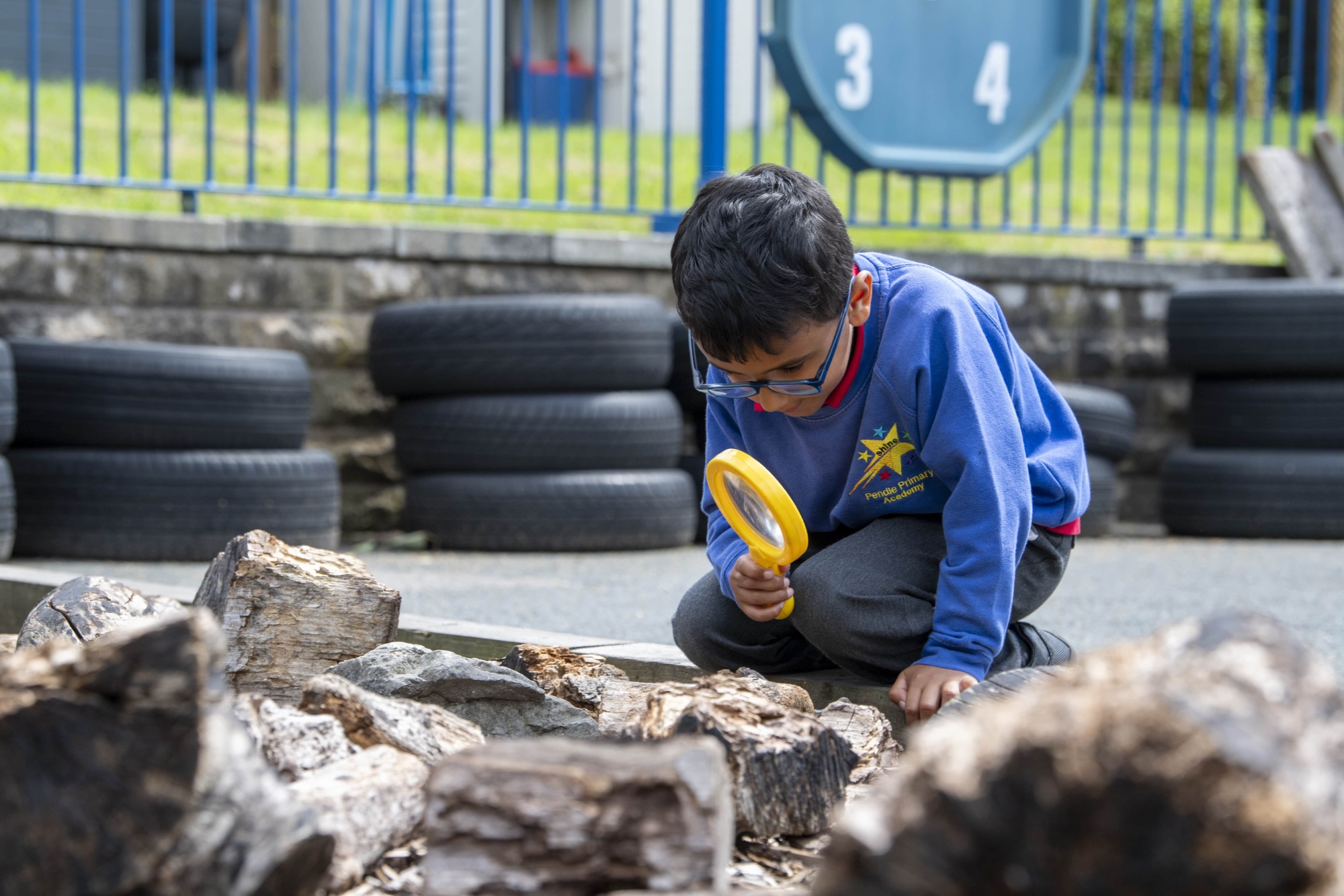 A child using a magnifying glass to look for bugs in a garden