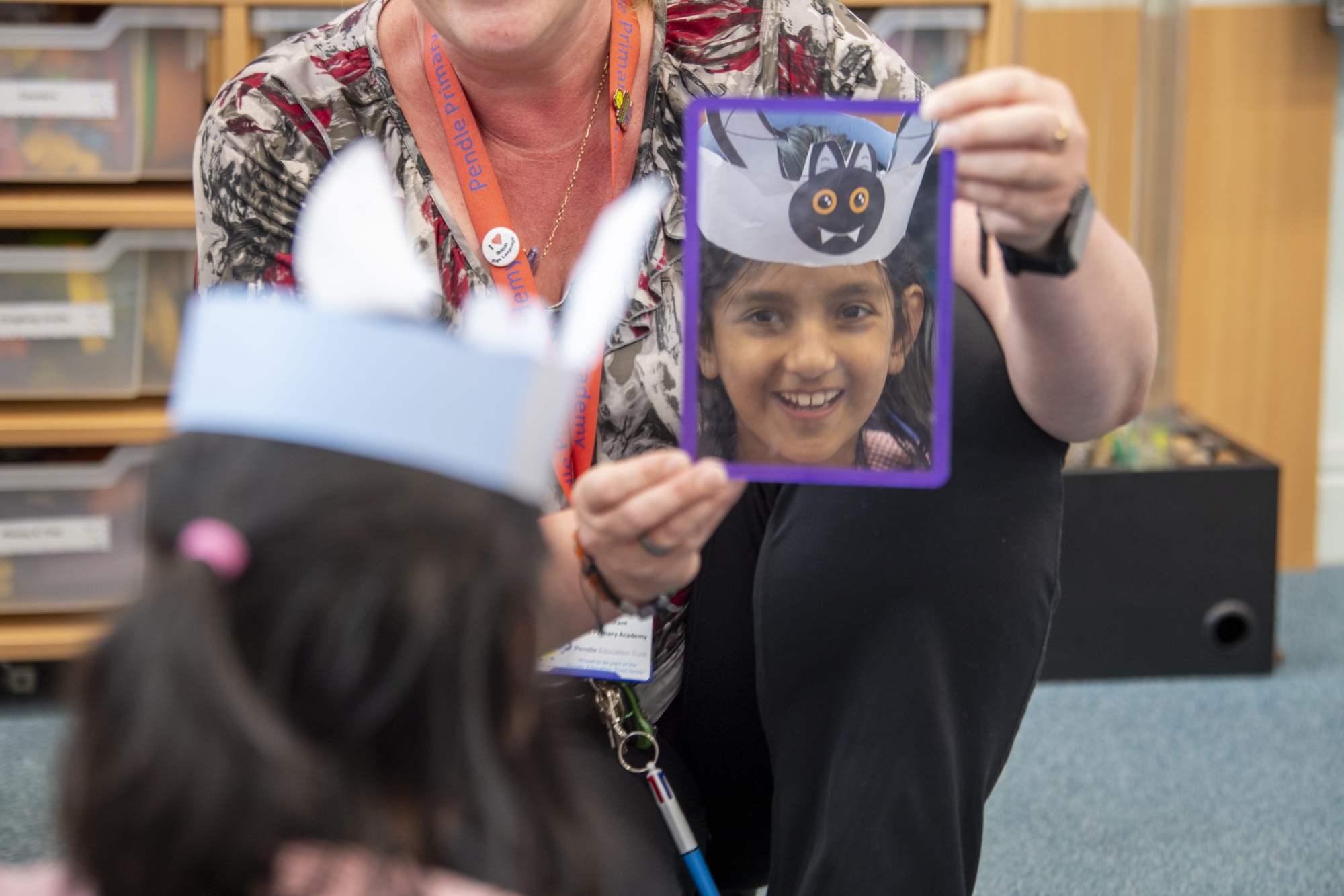 A teacher showing a child wearing a Halloween head dress their reflection in a mirror
